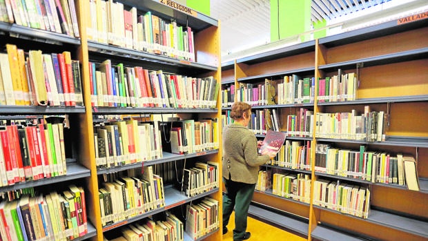 Una mujer consulta un ejemplar en una biblioteca de Valladolid